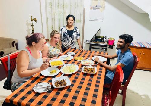a group of people sitting around a table eating food at Jm Resort in Dambulla