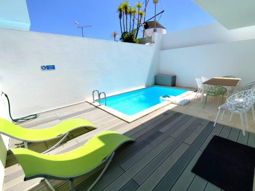 a swimming pool with green chairs and a table at Sunset Street Beach house in Lourinhã