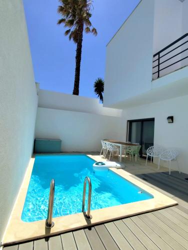 a swimming pool with a palm tree in a house at Sunset Street Beach house in Lourinhã