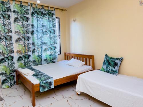 two twin beds in a room with a window at NYALI-HOMESTAY BEACH VIEW ROOMs AND APARTMENT WITH SWIMMING POOL in Mombasa