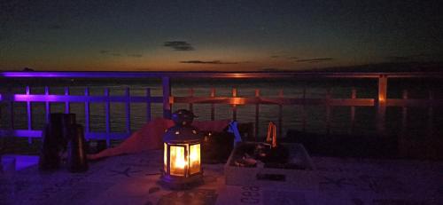 a lantern sitting on a table with the ocean at night at SUNSET ROOM AT FRONT BEACH - HABITACION EN LA PLAYA en Piso compartido in Tavernes de Valldigna