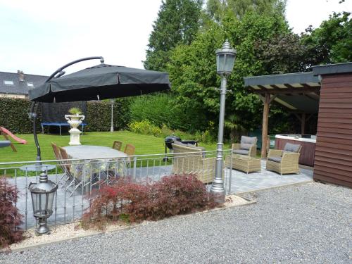 a patio with a table and an umbrella and chairs at Gite les bons amis in Plombières