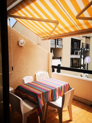 d'une table et de chaises avec un tissu de table rayé sur le balcon. dans l'établissement Résidence Parc Et Avenue Dominica - Appartement 2 pièces 4 couchages LE BARCARES - CLIMATISATION EN OPTION MAE-5784, au Barcarès
