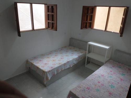 a small room with two beds and two windows at Casa Praia BRISAMAR in Maragogi