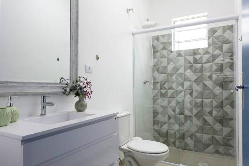 a white bathroom with a toilet and a sink at Casa Acuri in Jacareí