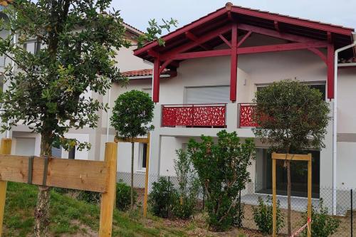 a house with a red balcony and a fence at location appartement in Soustons