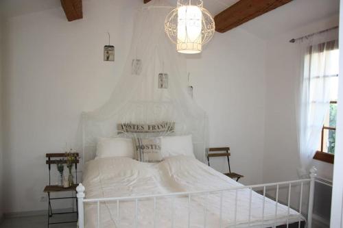 - un lit blanc dans une chambre blanche dotée d'un lustre dans l'établissement Small vineyard in Provence, au Thoronet