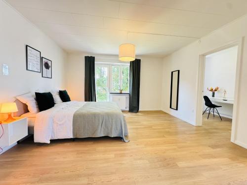 a white bedroom with a bed and a desk at aday - Solsortvej Suite 1 Randers in Randers