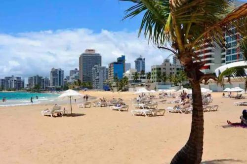 a beach with chairs and a palm tree and buildings at Santurce Studios Newly Renovated 6 in San Juan