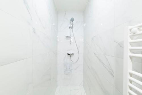 La salle de bains blanche est pourvue d'une douche et de murs en marbre blanc. dans l'établissement BELLE DE MAI - Gare st Charles, à Marseille