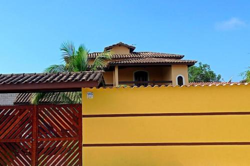 a yellow fence with a house behind it at Sobrado Quintal Grande 10 min do Centro in Caraguatatuba