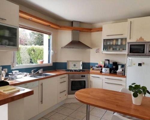 une cuisine avec des armoires blanches et une table en bois dans l'établissement Villa bord de mer, à Fouesnant
