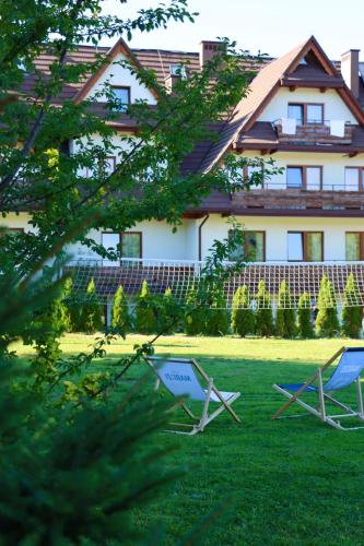 two lawn chairs in front of a house at Domki w Białce pod Basenami, 50 m od term i wyciągów in Białka Tatrzanska