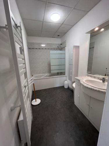 La salle de bains blanche est pourvue d'un lavabo et d'une baignoire. dans l'établissement Gîtes des travailleurs et estivants, à Grand-Fort-Philippe