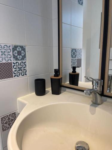 une salle de bain blanche avec un lavabo et un miroir dans l'établissement La Pépite, à Montbéliard