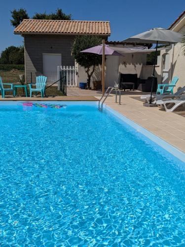 une piscine bleue avec des chaises bleues et un parasol dans l'établissement Le Petit chalet - 2 étoiles au classement tourisme, à Birac-sur-Trec