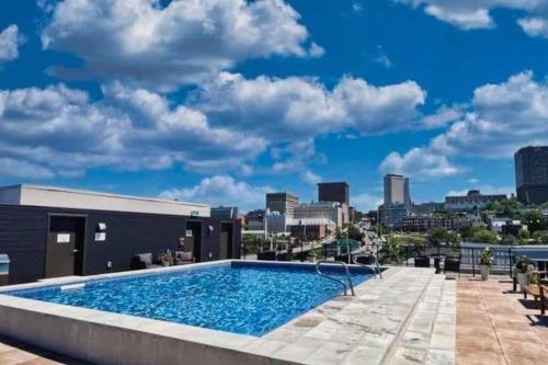a swimming pool on top of a building with a city skyline at 1CH - Rooftop pool - Kitchen - Smart TV - Gym - 750m QC in Quebec City