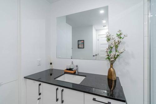 a white bathroom with a sink and a mirror at 1CH - Rooftop pool - Kitchen - Smart TV - Gym - 750m QC in Quebec City