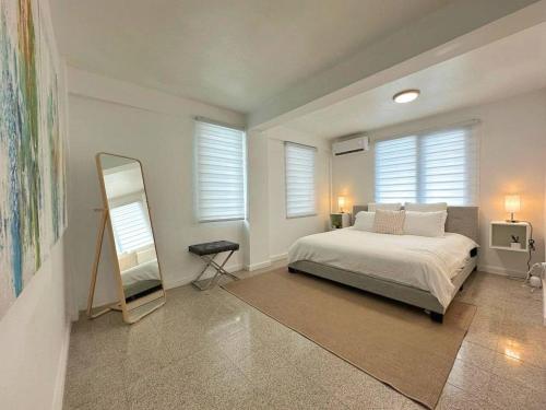 a bedroom with a bed and a mirror and windows at Beautifully Renovated 3 Rooms Home I in San Juan