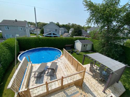 a backyard with a swimming pool with chairs and a fence at Lovely cottage with heated swimming pool in Quebec City