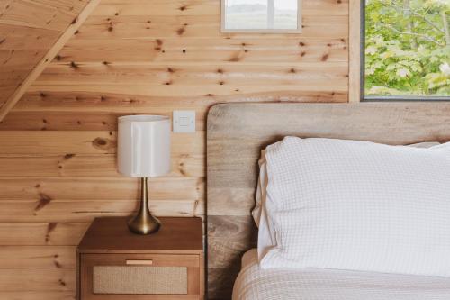 a bedroom with a bed and a lamp on a night stand at The Tree Houses at Madeira in Fife in Pittenweem