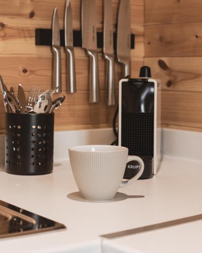 a kitchen counter with a cup and a cell phone on it at The Tree Houses at Madeira in Fife in Pittenweem