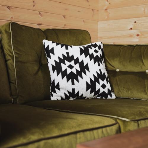 a black and white pillow on a green couch at The Tree Houses at Madeira in Fife in Pittenweem