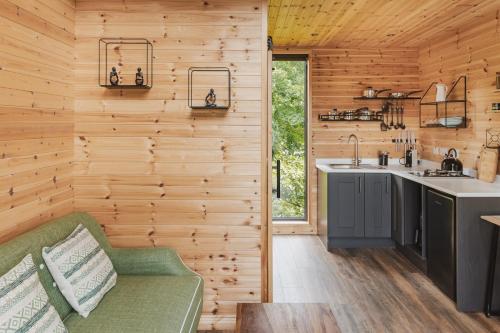 a kitchen with wooden walls and a green couch at The Tree Houses at Madeira in Fife in Pittenweem