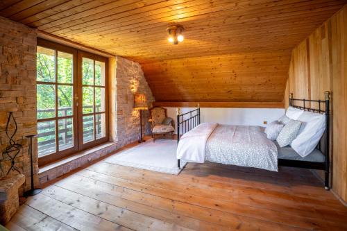 a bedroom in a log cabin with a bed and windows at Domček Ľúbezný in Banská Štiavnica