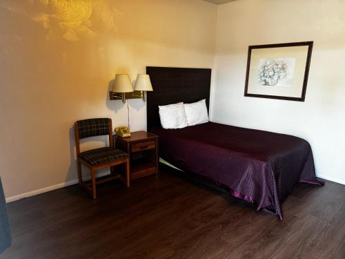a hotel room with a bed and a chair at Heritage Inn in Uniontown
