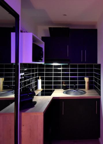 une cuisine avec deux lavabos et un éclairage violet dans l'établissement Appart Spa Sauna Balnéo exterieur au Cœur du Havre, au Havre