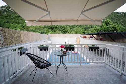 a patio with a table and a chair on a balcony at Villa Počitelj in Čapljina