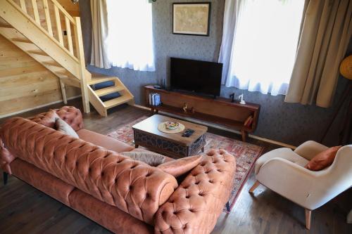 a living room with a large couch and a television at Adria Nord Chalets in Žabljak