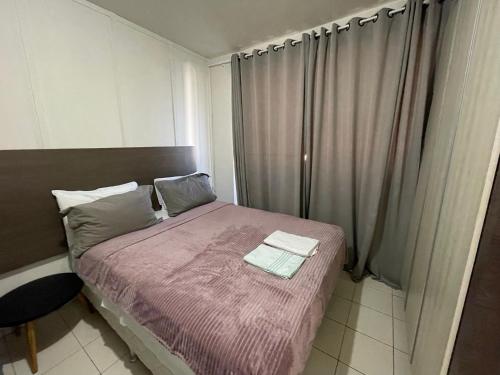 a small bedroom with a bed with a pink blanket at Link Araranguá in Araranguá