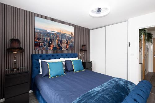 a bedroom with a blue bed with a painting on the wall at The East Retreat in Manchester