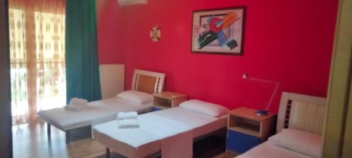 a living room with red walls and white beds at Vila Tahiri in Golem