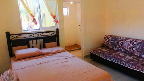 een slaapkamer met een bed en een bank bij Villa del Sol in Barra de Potosi