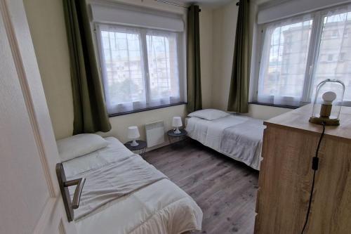 une chambre avec deux lits et deux fenêtres dans l'établissement Les Guillemots, au Tréport