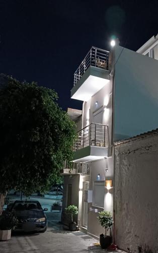 a white apartment building with a balcony at night at Roummi Suite Mirtos in Myrtos