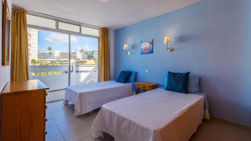 a hotel room with two beds and a large window at Tagoror Beach Apartments - Adults Only in Playa del Ingles