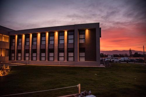 a large building with a sunset in the background at Amerian Chacras de Coria in Chacras de Coria