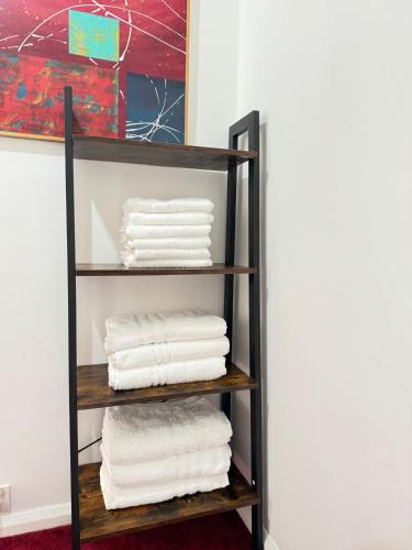 a black towel rack with white towels at Cosy Inn near Luton Station, Mall and Luton Airport 10 Min in Luton