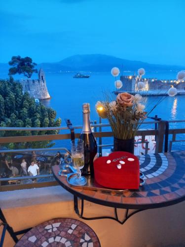 a table with a bottle of wine and flowers on a balcony at Casa da Sogno Elegant Studio in Nafpaktos