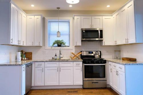 a white kitchen with white cabinets and appliances at BOUTIQUE GARDEN HOUSE CHICAGO 3-STORY sleeps 12 in Chicago