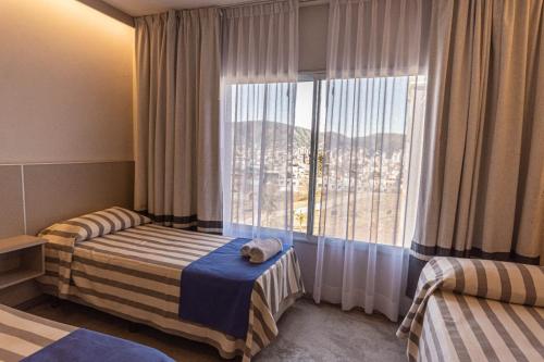 a hotel room with two beds and a large window at Enjoy 360 in Villa Carlos Paz