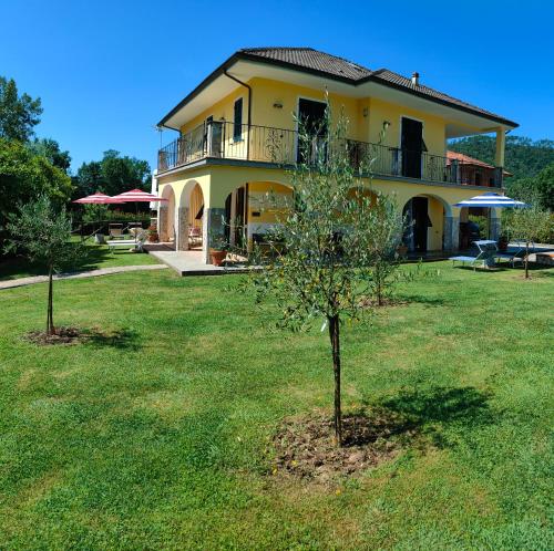 a yellow house with a tree in the yard at Maison du VALe in Sesta Godano