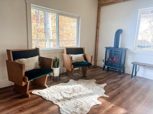 a living room with two chairs and a wood stove at Lakeside Cabin - Serene Retreat with Lake Monroe Views and Wraparound Deck in Brown County in Nashville