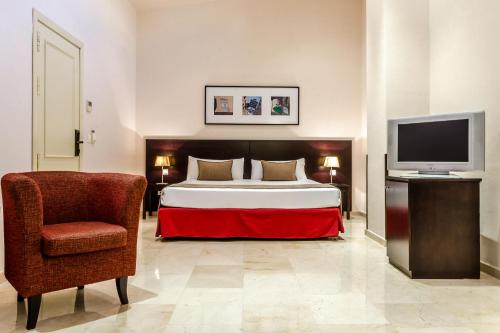 - une chambre avec un lit, une chaise et une télévision dans l'établissement Exe Suites 33, à Madrid