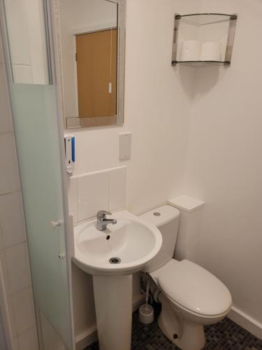 a white bathroom with a toilet and a sink at Heart of City DE1 Studio Apartment in Derby