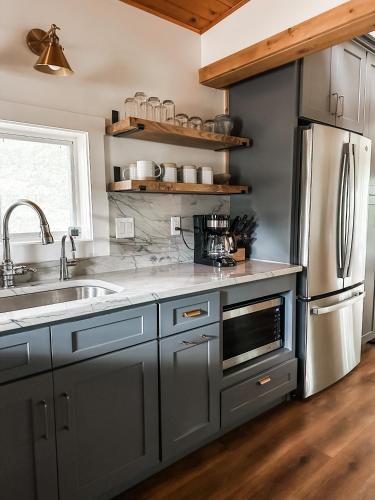a kitchen with gray cabinets and a stainless steel refrigerator at Lakeside Cabin - Serene Retreat with Lake Monroe Views and Wraparound Deck in Brown County in Nashville